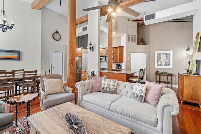 living room featuring beam ceiling, a high ceiling, wood-type flooring, and ceiling fan with notable chandelier