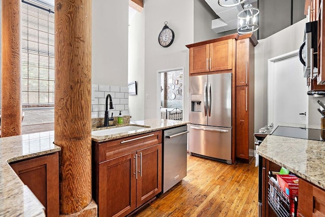 kitchen with tasteful backsplash, light hardwood / wood-style flooring, light stone counters, and stainless steel appliances