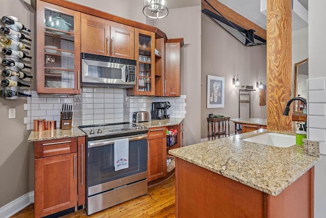 kitchen featuring light stone countertops, light hardwood / wood-style floors, beamed ceiling, sink, and appliances with stainless steel finishes