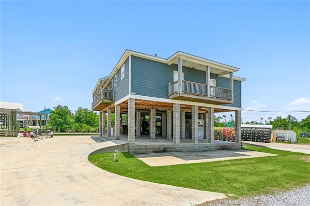 rear view of house featuring a balcony and a lawn