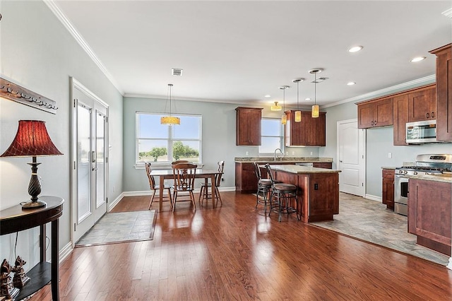 kitchen featuring a breakfast bar area, decorative light fixtures, a kitchen island, dark hardwood / wood-style flooring, and stainless steel appliances