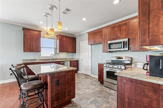 kitchen with decorative light fixtures, crown molding, light stone countertops, and stainless steel appliances