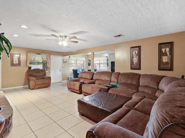 tiled living room with ceiling fan, a healthy amount of sunlight, and a textured ceiling