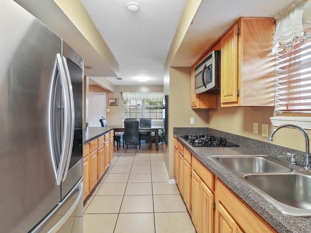 kitchen featuring sink, light tile patterned floors, a textured ceiling, and appliances with stainless steel finishes