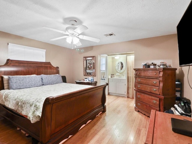 bedroom with ensuite bath, ceiling fan, a textured ceiling, and light wood-type flooring