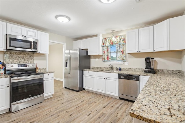 kitchen with appliances with stainless steel finishes, white cabinetry, sink, and light wood-type flooring