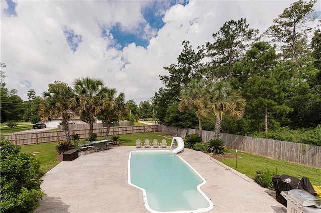 view of swimming pool featuring a patio area, a yard, and a water slide