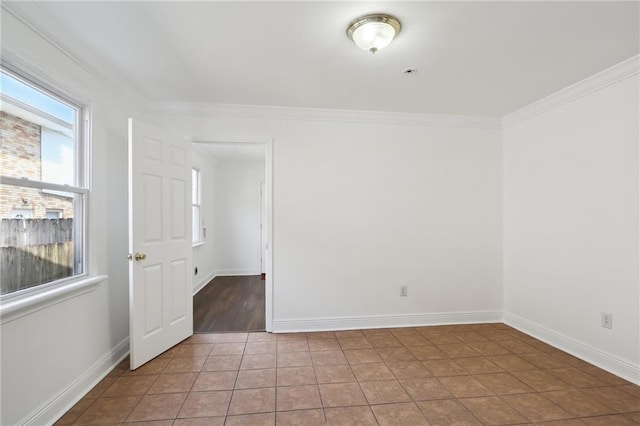 tiled spare room featuring ornamental molding and baseboards