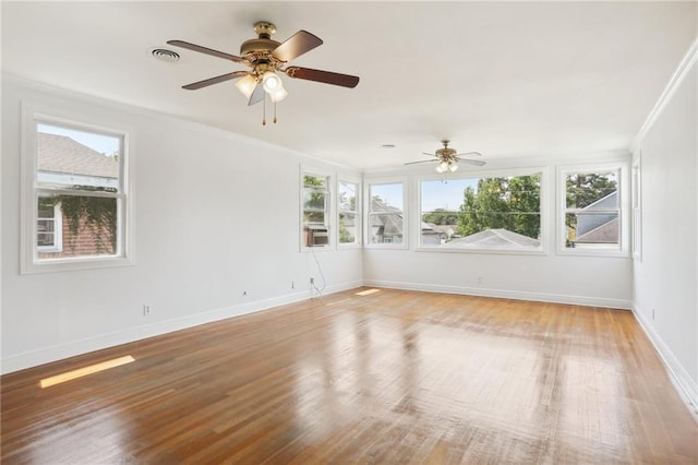 empty room with ceiling fan, crown molding, baseboards, and wood finished floors