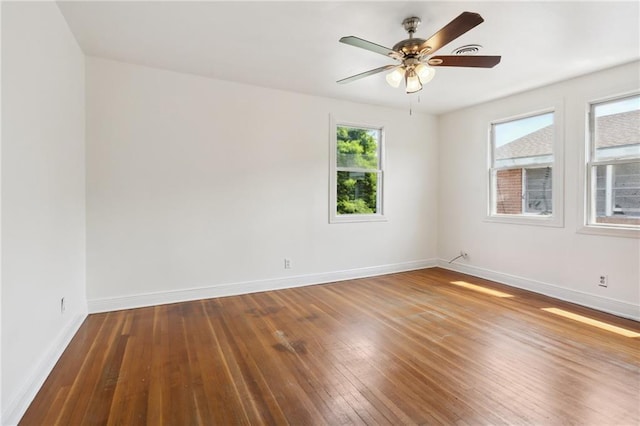 spare room featuring a ceiling fan, visible vents, baseboards, and wood finished floors