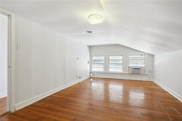 interior space with lofted ceiling, cooling unit, baseboards, and wood finished floors