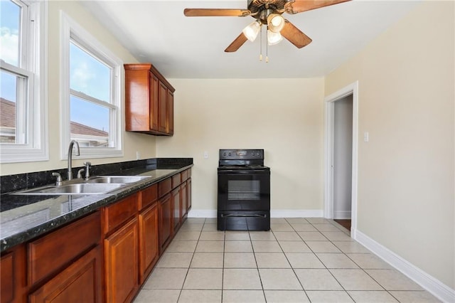 kitchen featuring light tile patterned flooring, a sink, baseboards, black electric range oven, and dark stone counters