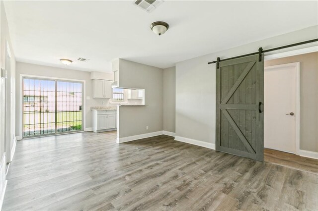 empty room with a barn door and wood-type flooring