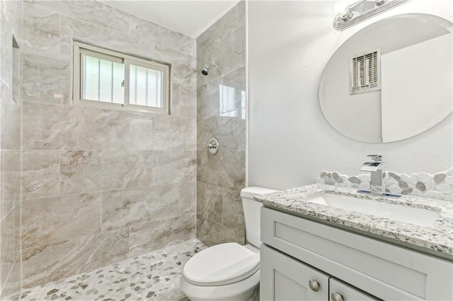 bathroom featuring vanity, tiled shower, and toilet