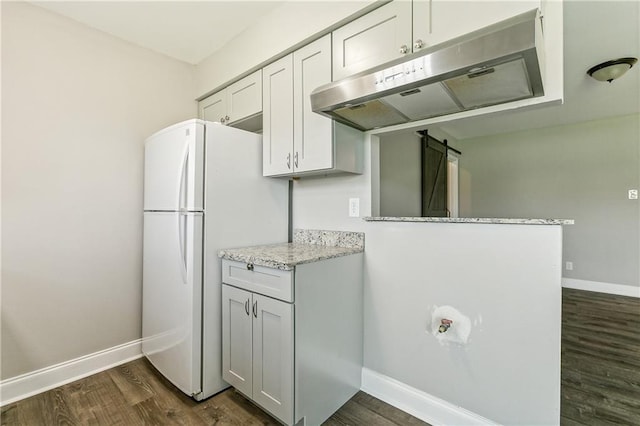 kitchen featuring dark hardwood / wood-style floors, white refrigerator, light stone counters, white cabinets, and kitchen peninsula