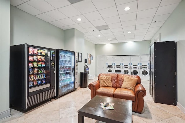 living room featuring washer and clothes dryer, light tile flooring, and a drop ceiling