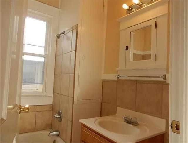 bathroom featuring vanity, shower / bath combination, and tile walls