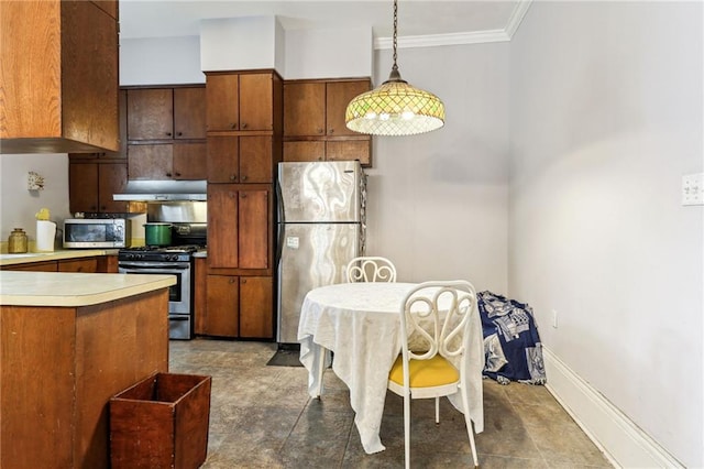 kitchen with hanging light fixtures, appliances with stainless steel finishes, ornamental molding, and dark tile patterned floors