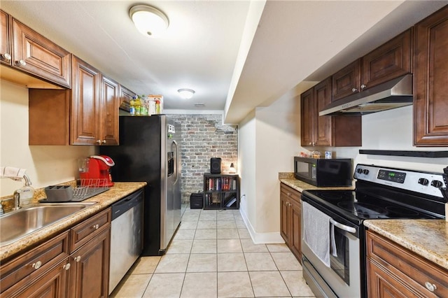 kitchen featuring stainless steel appliances, sink, brick wall, and light tile patterned floors