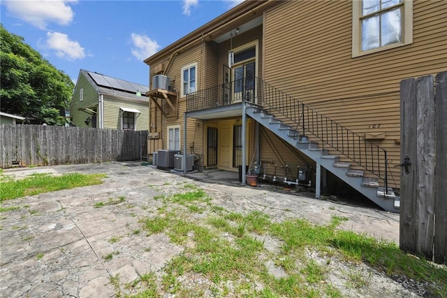 back of property with a patio, central air condition unit, and solar panels