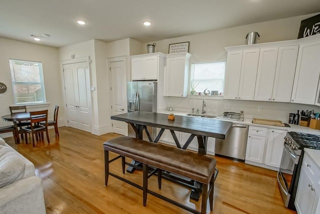 kitchen featuring a sink, recessed lighting, light wood-style floors, appliances with stainless steel finishes, and white cabinets