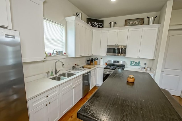 kitchen with a sink, stainless steel appliances, dark wood-style floors, and white cabinetry