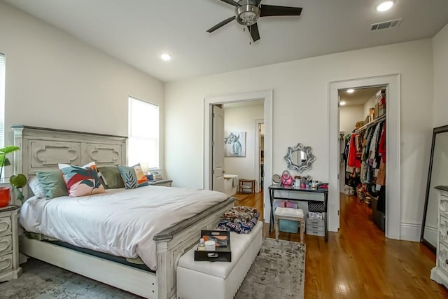 bedroom with wood finished floors, visible vents, a ceiling fan, recessed lighting, and a walk in closet