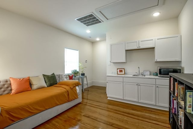 kitchen featuring visible vents, light wood-style flooring, a sink, stainless steel microwave, and light countertops