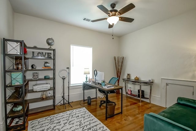 office space with visible vents, baseboards, a ceiling fan, and wood finished floors