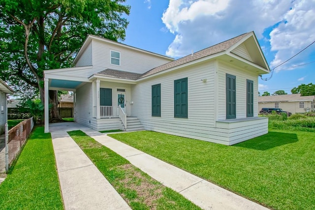 view of front of home with a shingled roof, a front lawn, fence, and a carport