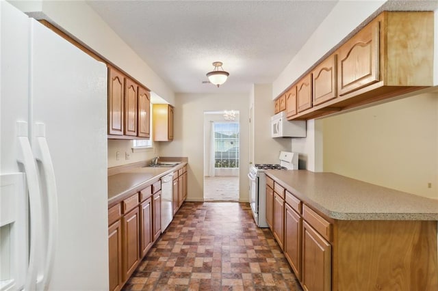 kitchen with a textured ceiling, sink, and white appliances