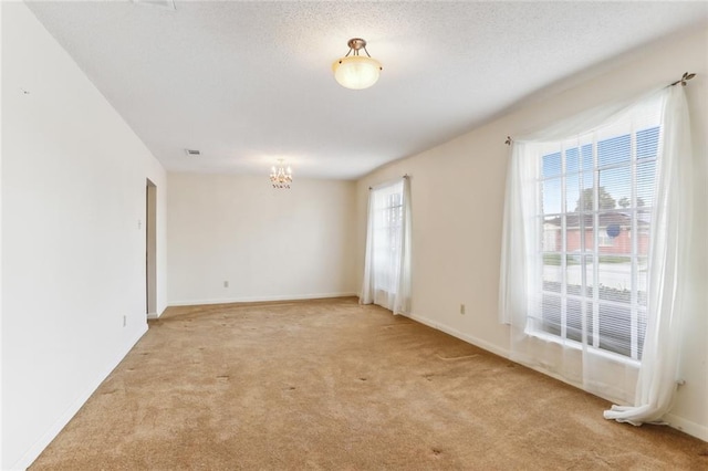 carpeted empty room with a notable chandelier