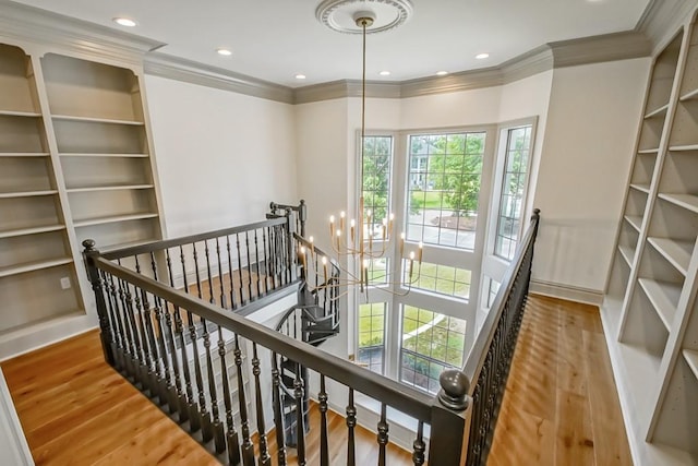 corridor with a chandelier, hardwood / wood-style floors, and crown molding