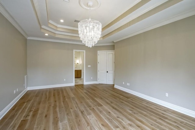 unfurnished room featuring a raised ceiling, crown molding, hardwood / wood-style floors, and a notable chandelier