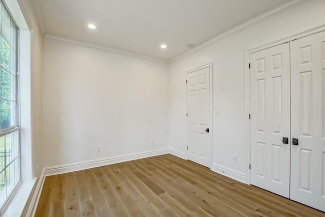 unfurnished bedroom featuring hardwood / wood-style flooring, ornamental molding, and two closets