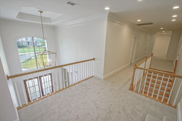 hall featuring crown molding, light carpet, and a chandelier