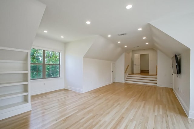 additional living space featuring built in shelves, light hardwood / wood-style flooring, and lofted ceiling