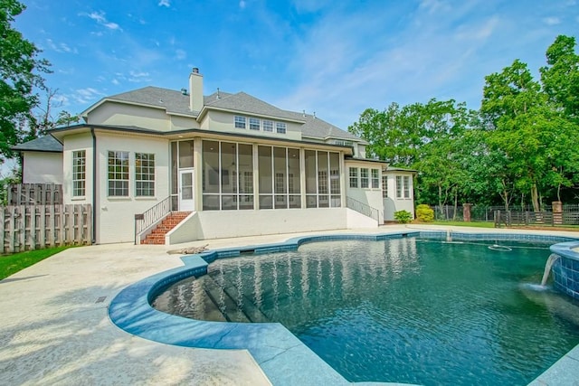 back of property with a sunroom, a fenced in pool, and pool water feature