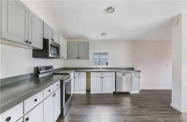 kitchen with gray cabinetry, dark wood-type flooring, stainless steel appliances, and sink