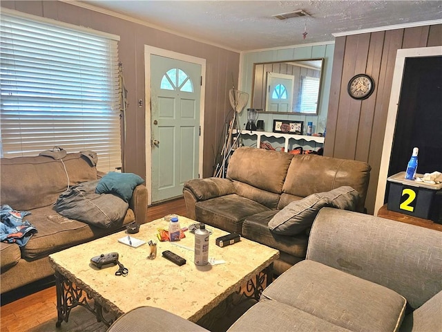 living room featuring crown molding, wooden walls, and hardwood / wood-style floors