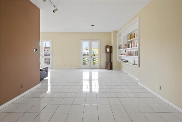 tiled spare room with built in shelves, track lighting, and french doors