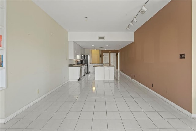 unfurnished living room with track lighting, sink, and light tile patterned floors