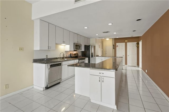 kitchen featuring sink, light tile patterned floors, stainless steel appliances, a center island, and white cabinets