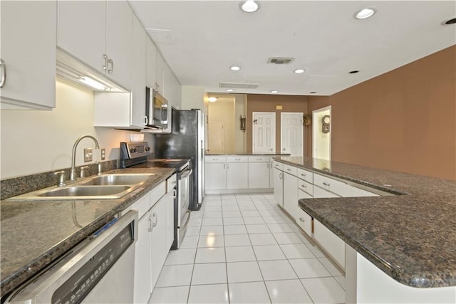 kitchen with appliances with stainless steel finishes, sink, light tile patterned floors, and white cabinets