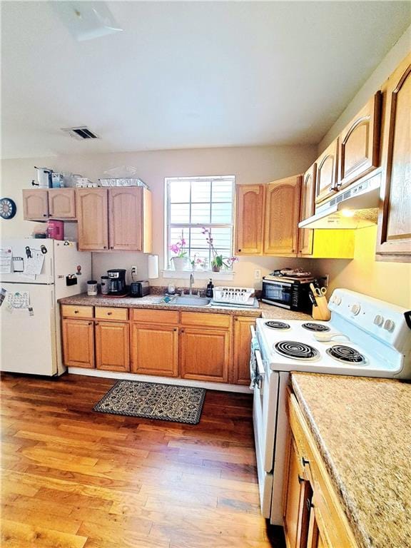 kitchen featuring white appliances, sink, and wood-type flooring