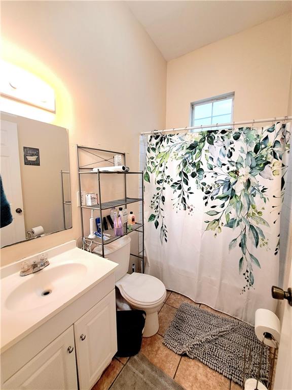 bathroom featuring tile flooring, toilet, and vanity