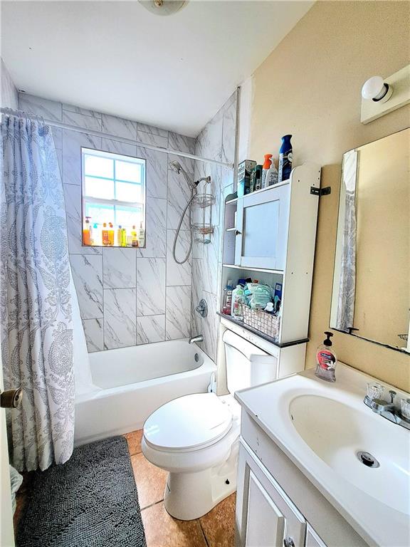 full bathroom with tile flooring, shower / tub combo with curtain, vanity, and toilet