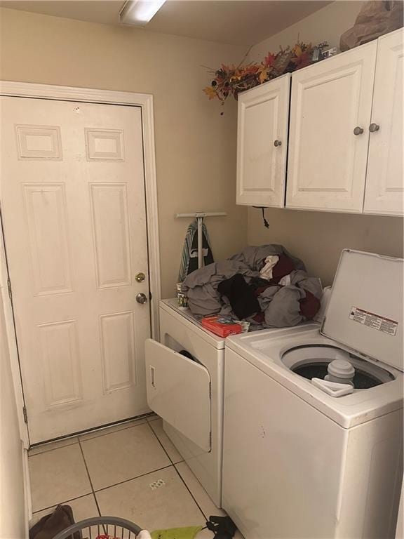 laundry room featuring independent washer and dryer, light tile flooring, and cabinets