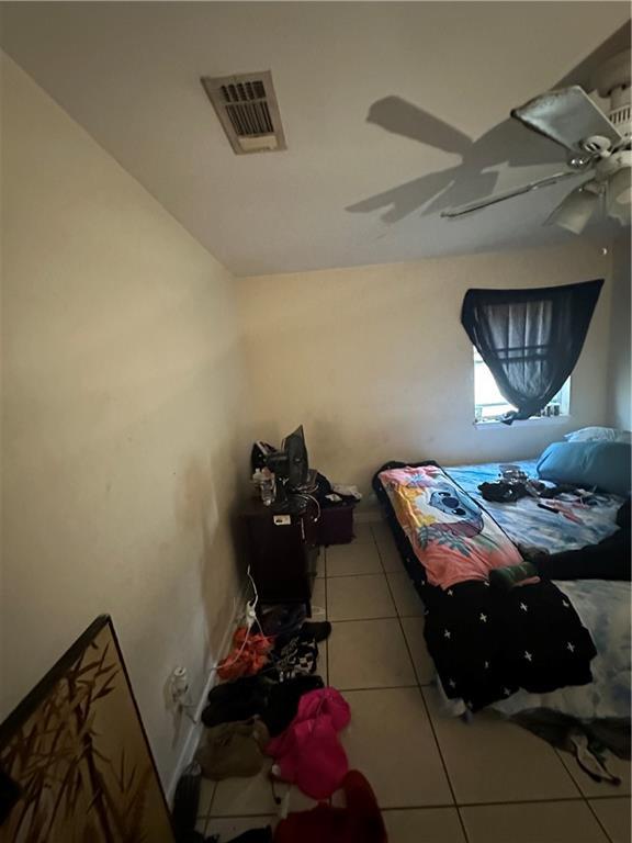 tiled bedroom featuring ceiling fan