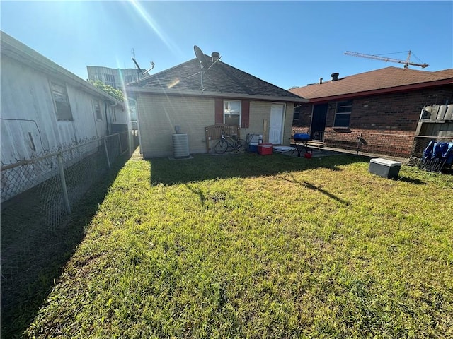 rear view of property featuring central AC and a lawn